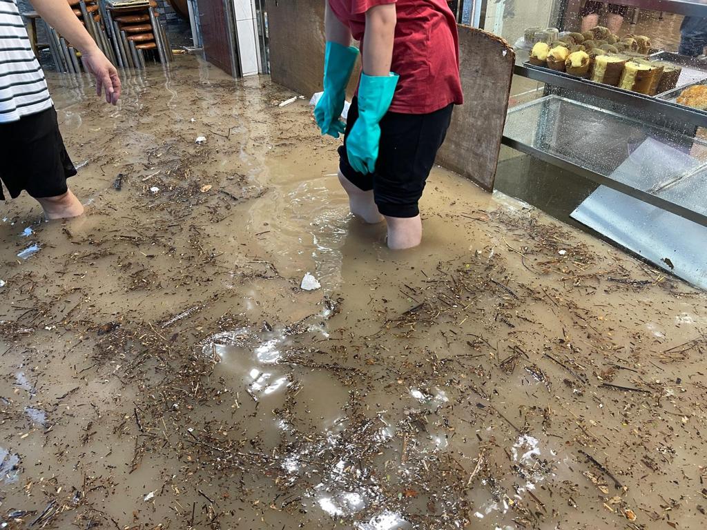 茶餐廳職員在黃泥水中忙於清理。(受訪者提供相片)