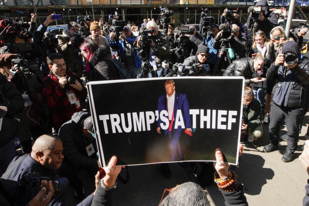 一名反特朗普的婦女在法院前舉著海報示威，指特朗普是賊。AP