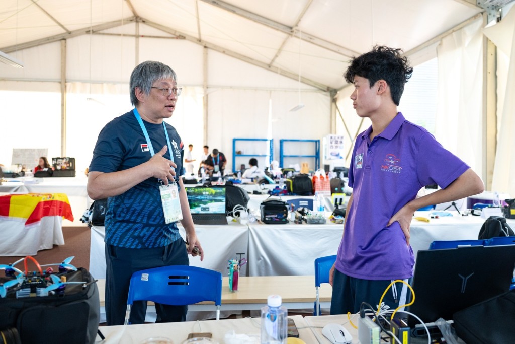 港隊團長黃寶基（左）到場支持17歲飛航運動無人機競速賽代表關竣仁。相片由港協暨奧委會提供