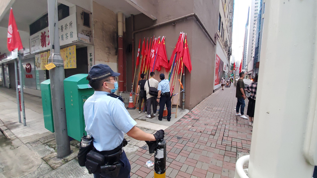 警員檢起國旗與區旗，扶正靠於一大廈外牆。