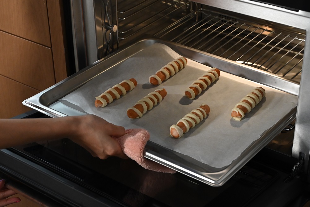 6. 用面条绕着整条香肠。   Wrap a strip of pastry around each sausage. 