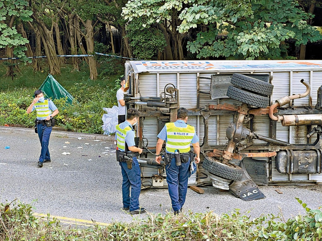 肇事貨車翻側路中，死者遺體被帳篷覆蓋。