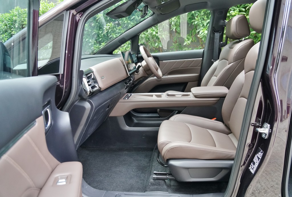 The interior features a beige and black color scheme with three rows of seats, including a two-plus-two-plus-three seat layout, and a modern dashboard with an electronic instrument cluster.