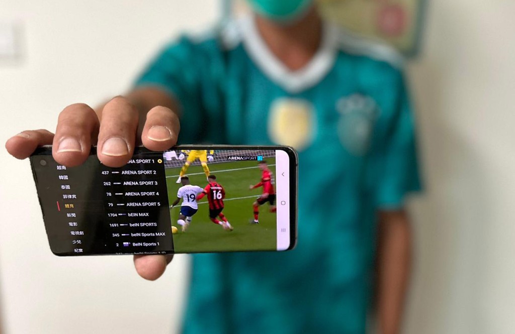 有購買了電視APP的青年展示手機畫面，當中有不少可觀看足球賽事和世界盃的外國電視頻道。(李建人攝)