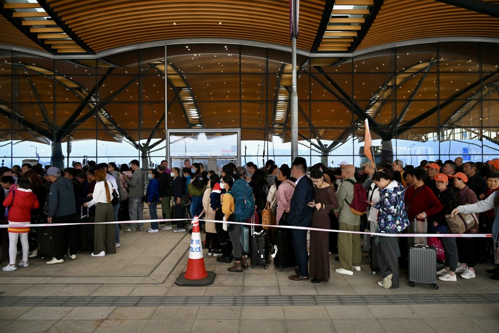 大批旅客在港珠澳大橋香港口岸外，排隊準備進入出境大堂過關前往珠海及澳門。蘇正謙攝