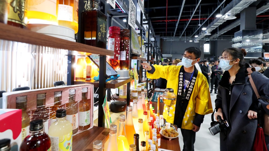 日本酒商工作人員（左）在上海舉辦的洽談會展示區介紹酒類產品。新華社