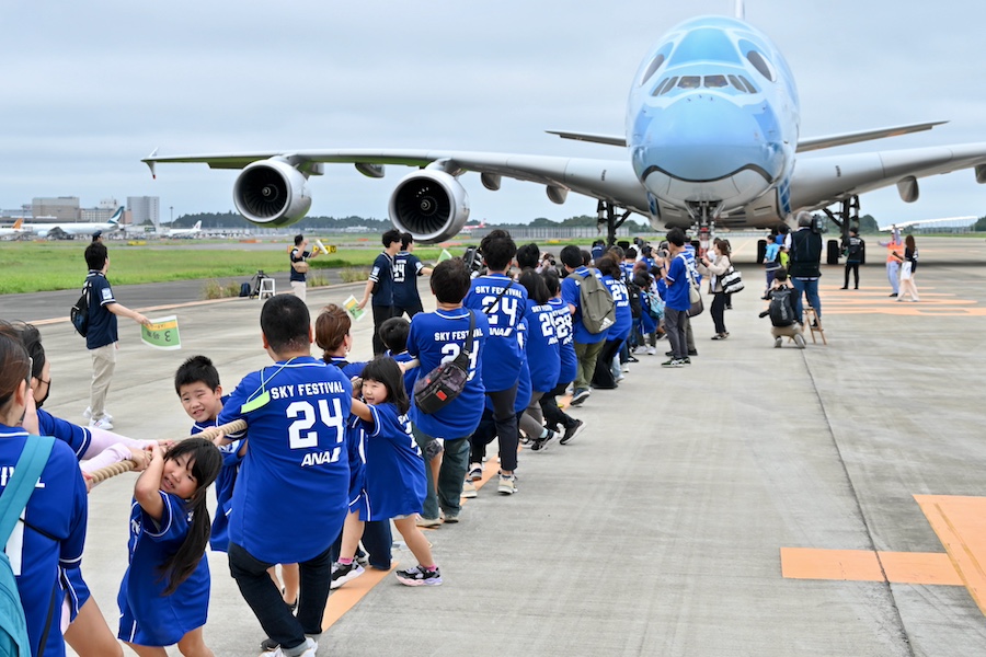 小学生与家长共同努力，拉动A380客机。（X@traicycom）