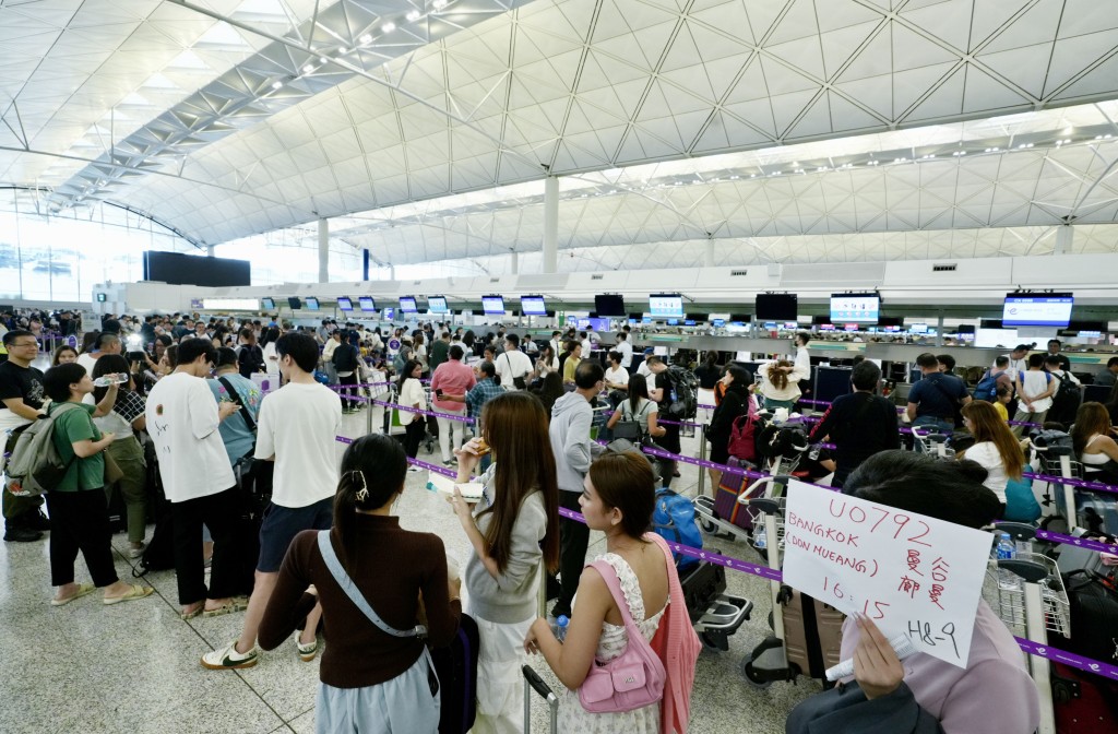 有航空公司職員用手寫牌安排乘客登機。劉駿軒攝