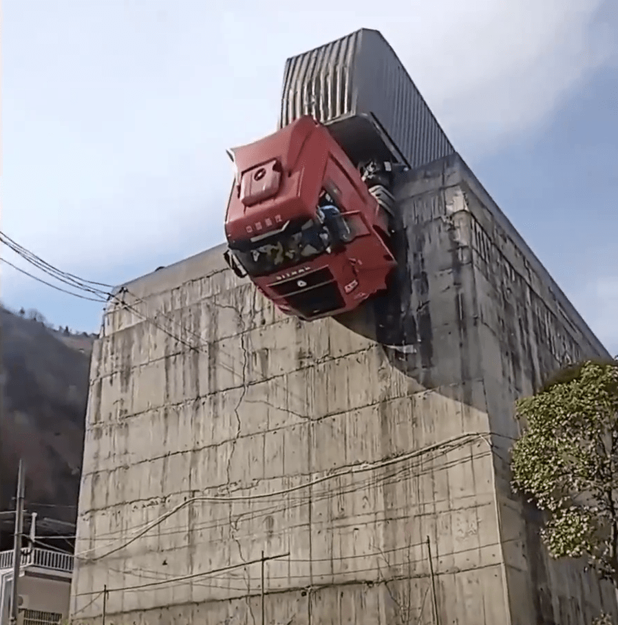 剎車失靈貨櫃車衝出公路，拖頭90°懸掛半空，司機受困，如身處懸崖。 陝西消防