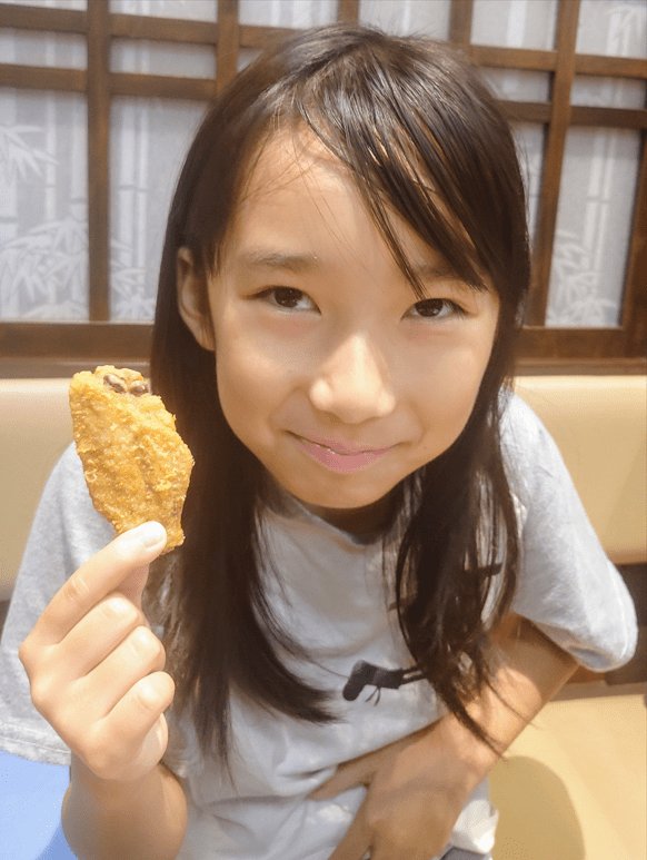 平田琉七手拿炸雞翼展露招牌純真笑容。
