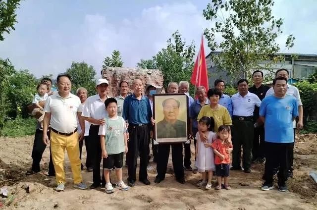 当地村民持毛泽东相前往雕像原址拜祭。