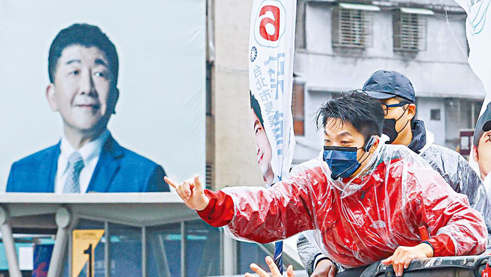 國民黨台北市長候選人蔣萬安（紅衣）昨天冒雨拜票。左方為民進黨對手陳時中的巨型宣傳板。