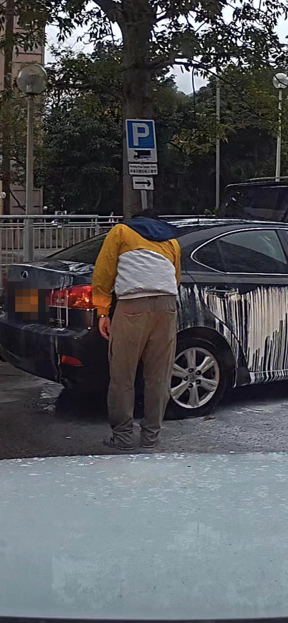 疑似车主手里拿著物品走到私家车前，似低头清洗车身。
