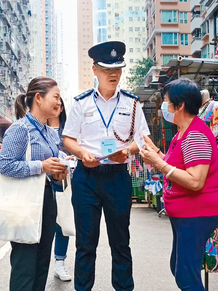 陳天柱總警司（中）與弘愛會主席曾卓兒（左）在北角春秧街派發防騙宣傳單張。