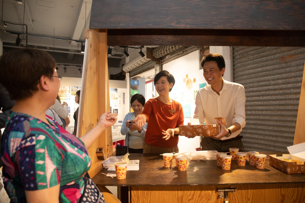 何永賢等人在的茶檔道具攤位向街坊派奶茶、蛋撻等。