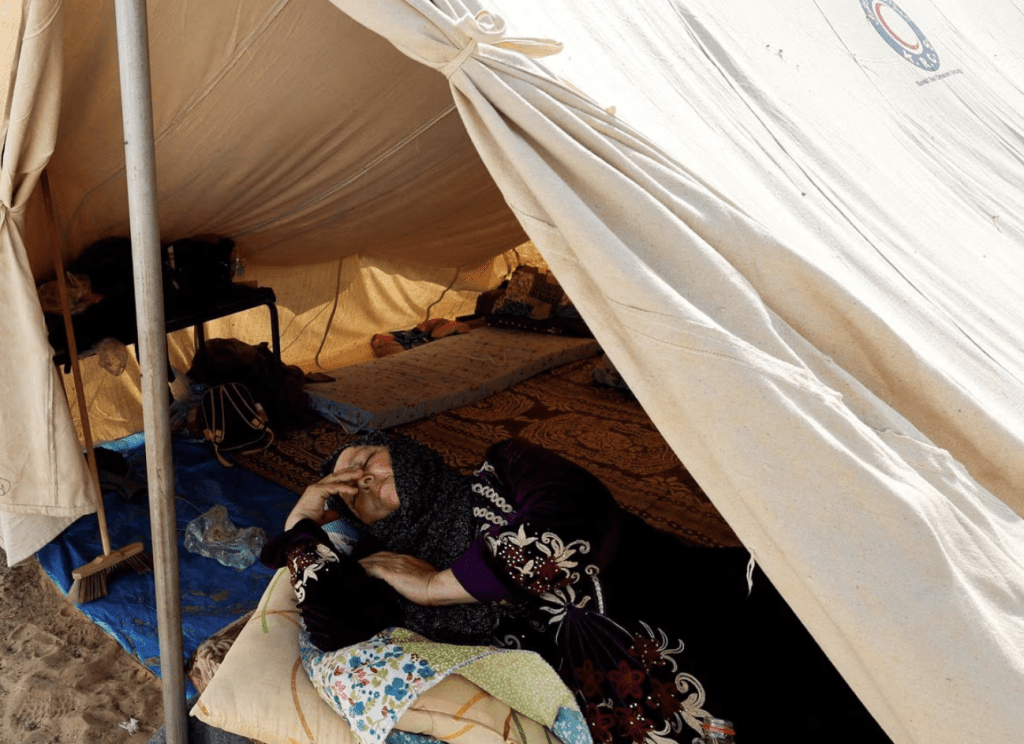在以色列呼籲加沙北部超過 100 萬平民向南遷移後，一名巴勒斯坦婦女在以色列的襲擊中逃離家園，在聯合國運營的中心的帳篷營地休息。加沙地帶南部，2023 年10 月23 日。路透社