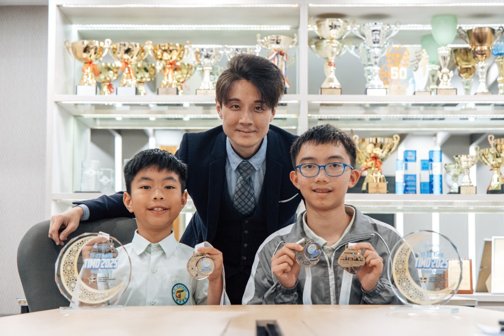 (左)張靖浩(Jeremy) TIMO 2025四年級組別世界季軍 (中)Dr Keff Chin 優才(楊殷有娣)書院數學科統籌主任、香港隊總領隊 (右)洪烺僖(Cryus) TIMO 2025七年級組別世界冠軍金(圖片來源:《親子王》) (左)張靖浩(Jeremy) TIMO 2025四年級組別世界季軍 (中)Dr Keff Chin 優才(楊殷有娣)書院數學科統籌主任、香港隊總領隊 (右)洪烺僖(Cryus) TIMO 2025七年級組別世界冠軍金(圖片來源:《親子王》)