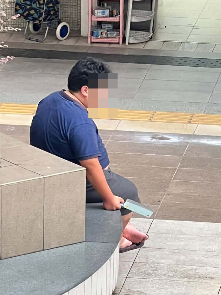一名身穿T恤短褲及拖鞋的男子坐在竹園南邨的平台石壆上。網上圖片 一名身穿T恤短褲及拖鞋的男子坐在竹園南邨的平台石壆上。網上圖片