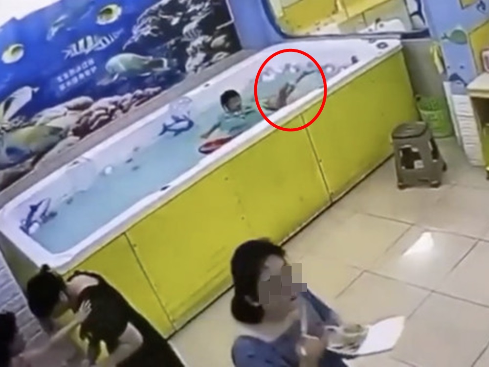 女童母親背着水池吃飯盒，完全沒發現女兒遇溺(紅圈)。影片截圖