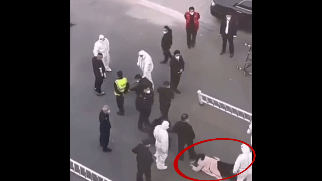 一名穿粉红外套的女子在镜头下方出现，被人推倒在地。