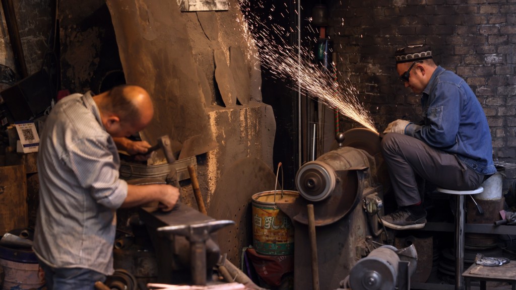 在新疆喀什古城景区铁业公社内，手艺人在制作铁器。  新华社