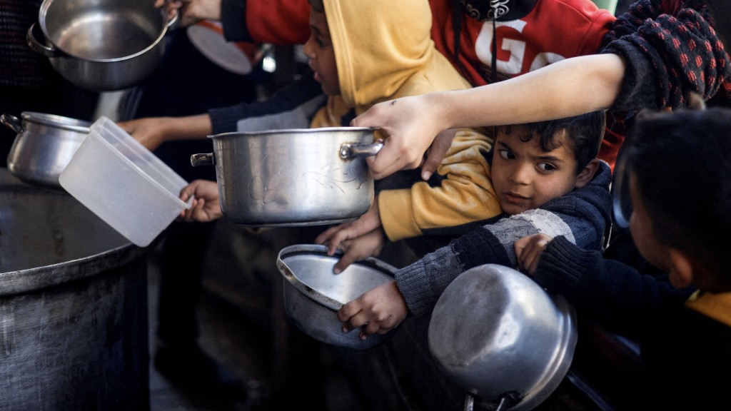 巴勒斯坦儿童带着容器去领取食物。 路透社