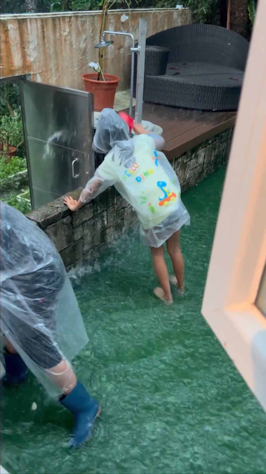 家姐着上雨衣幫手清理積水。