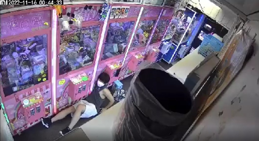 為求伸盡手的長度,灰衫青年甚至緊握心口,盡量讓右手伸進出入口內。(影片截圖)