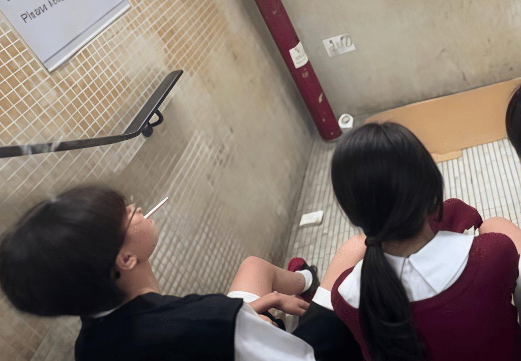 兩名身穿校服的年輕人在葵廣後樓梯吸煙。（受訪者提供）