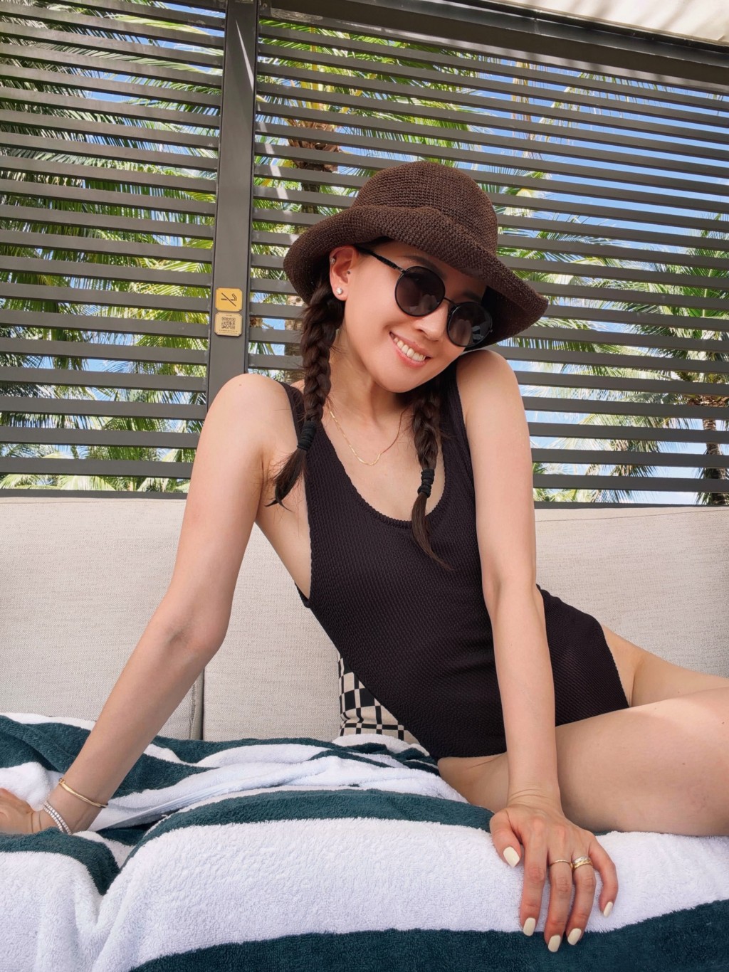任祉妍身穿一件頭黑色泳衣配草帽，在沙灘椅上展露招牌白滑美肌與甜笑。