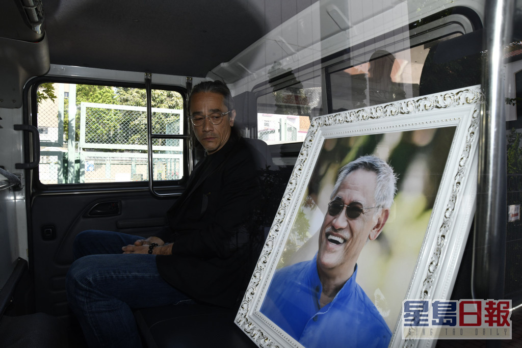 吳嘉龍在車內凝望亡父的遺照時，眼泛淚光。