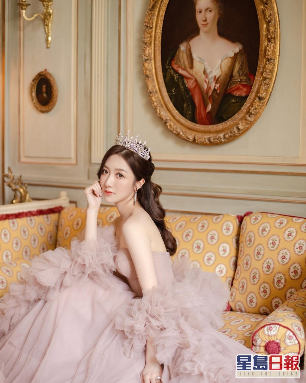 何依婷换上一袭粉红色低胸婚纱裙，裙摆与手袖位置采用荷叶边设计，加上头戴镶钻皇冠，俨如公主般梦幻。