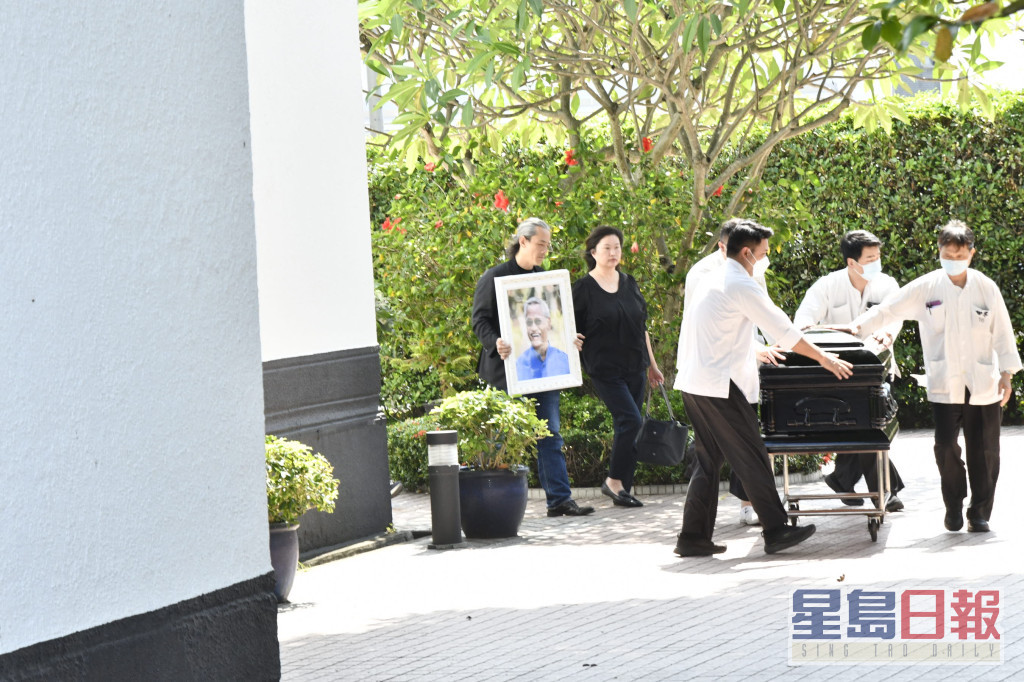 吴嘉龙捧着亡父吴耀汉的遗照，随灵柩步出教堂。