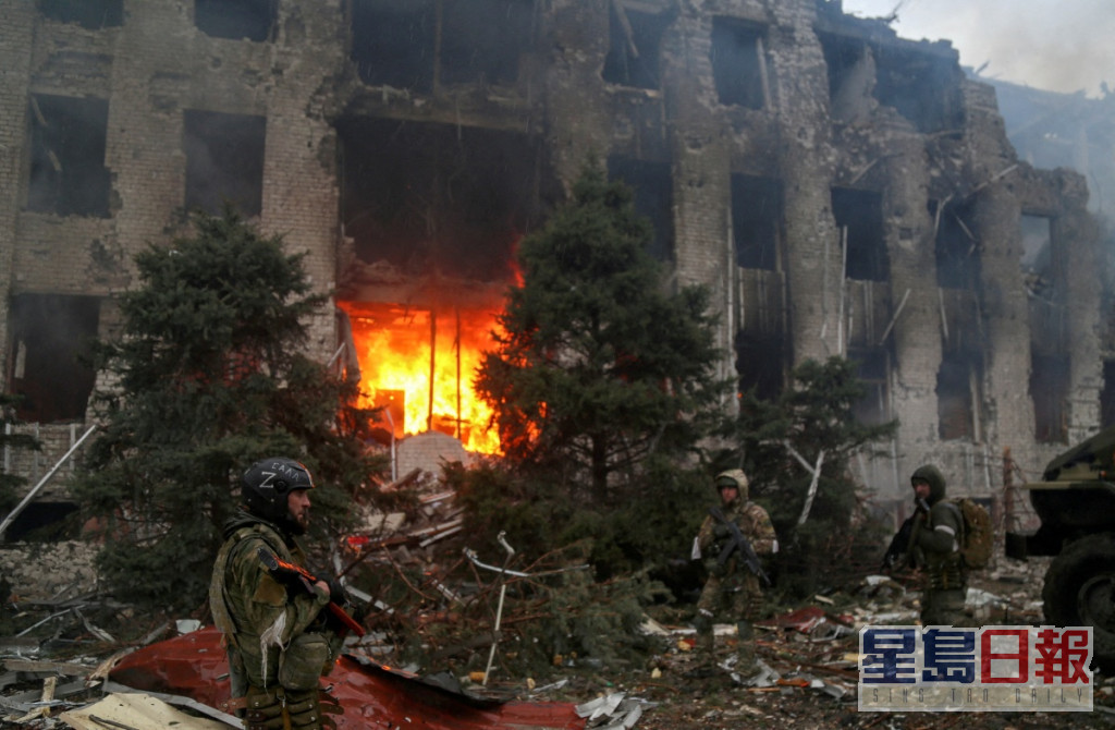 亲俄军队人员站在马里乌波尔一座被毁建筑前。REUTERS