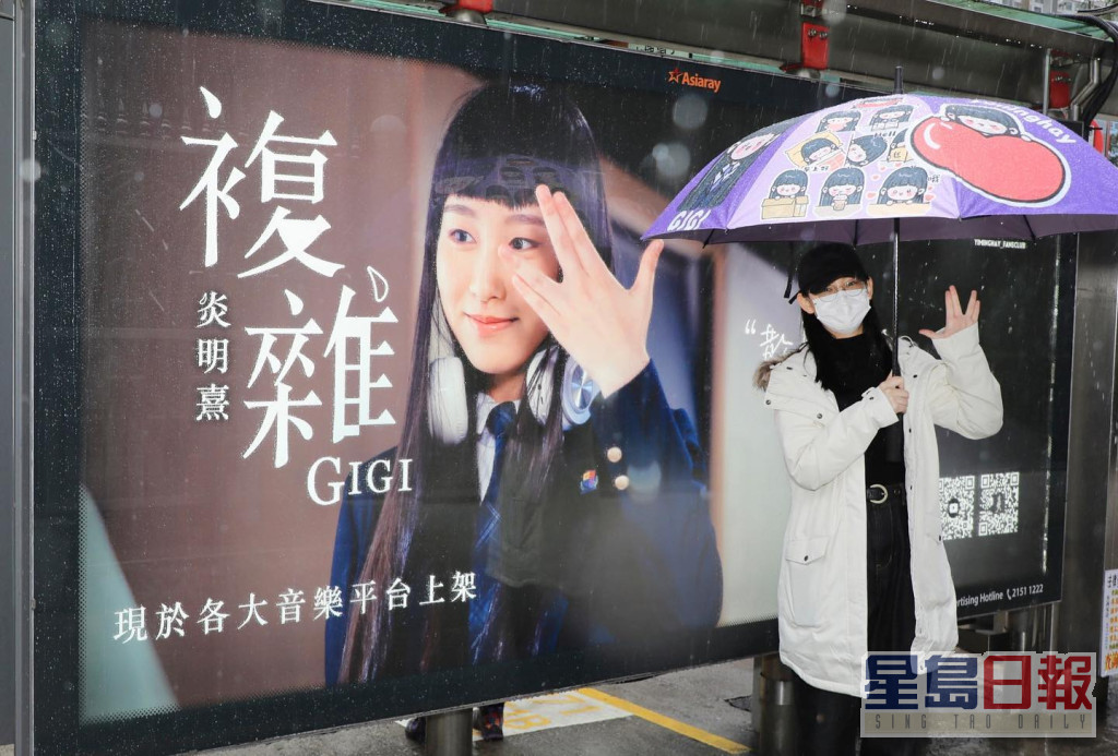 Gigi拿着有自己卡通公仔雨傘在燈箱前打卡。