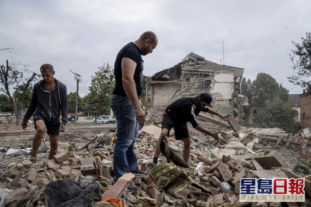 一个住宅区遭俄军炮击后居民在废墟欲寻回有用物品。AP