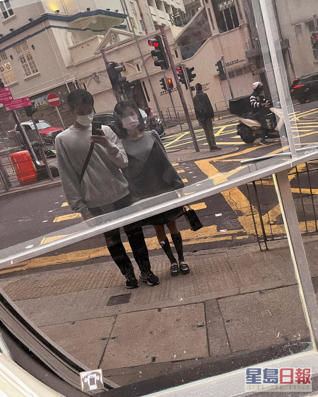 二人于大街上对住玻璃拍倒影合照，真系好似拍紧拖。