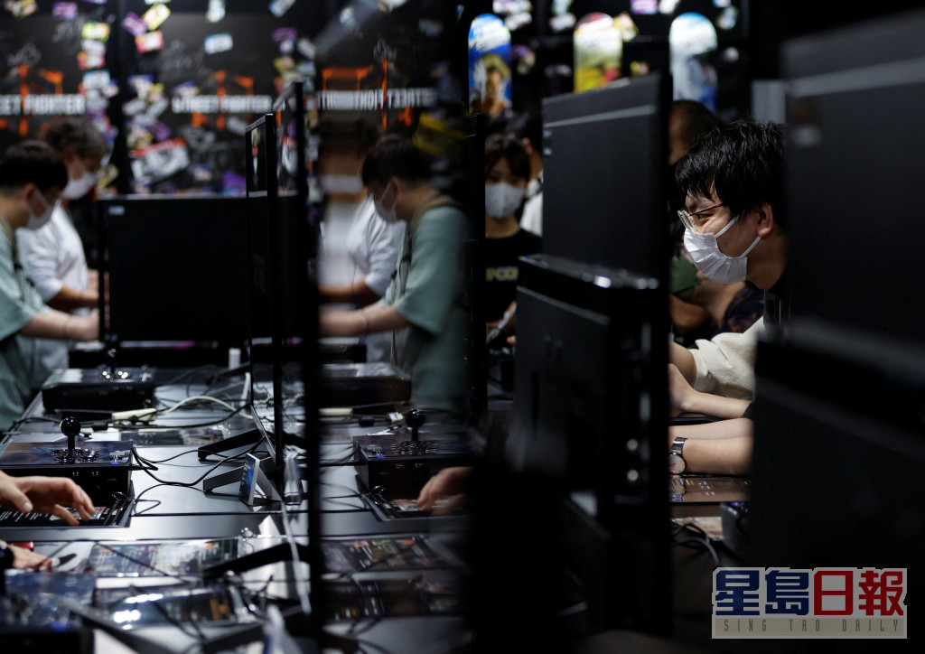 戴口罩的参观者在东京电玩展展位上尝试游戏设备。路透社图片