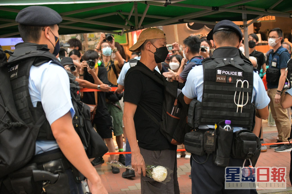 警員在銅鑼灣截查身穿黑衣手持白花的男子。