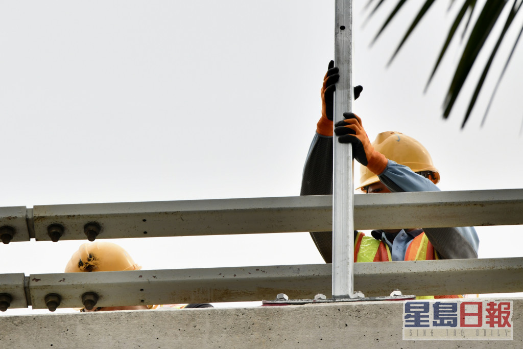 西九龙法院外行车天桥栏杆处，有工人正加装防护网。卢江球摄