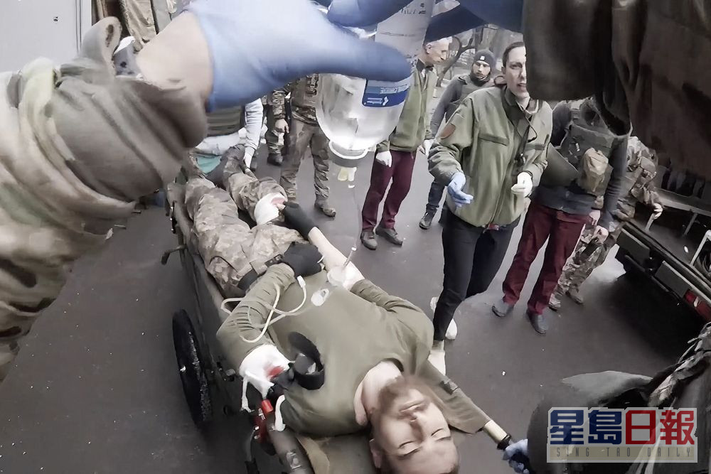 女軍醫用隨身攝錄機拍攝救治傷兵的實況。AP
