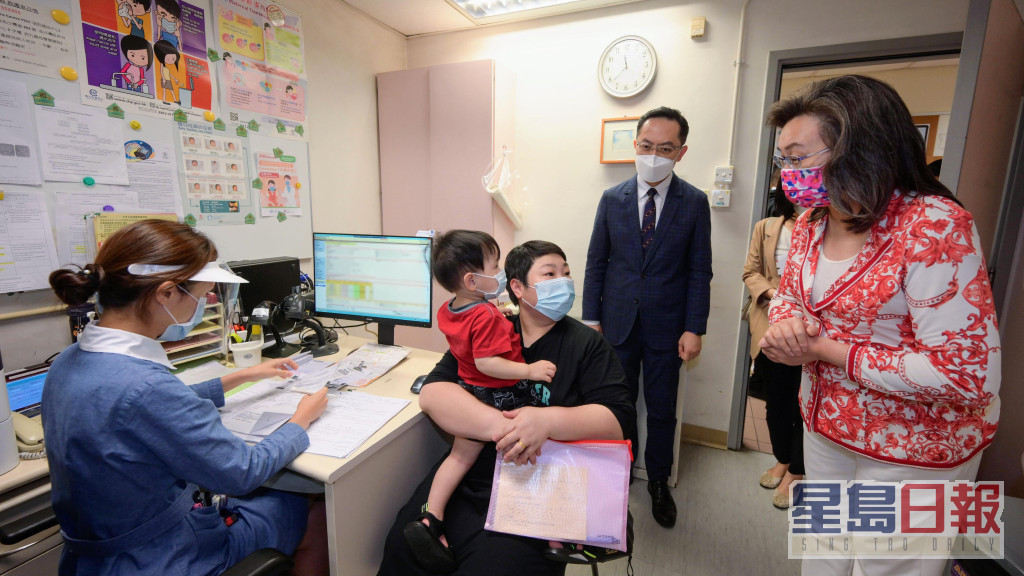楊何蓓茵（右一）向一名17個月大男童的家長介紹有關接種服務。政府圖片