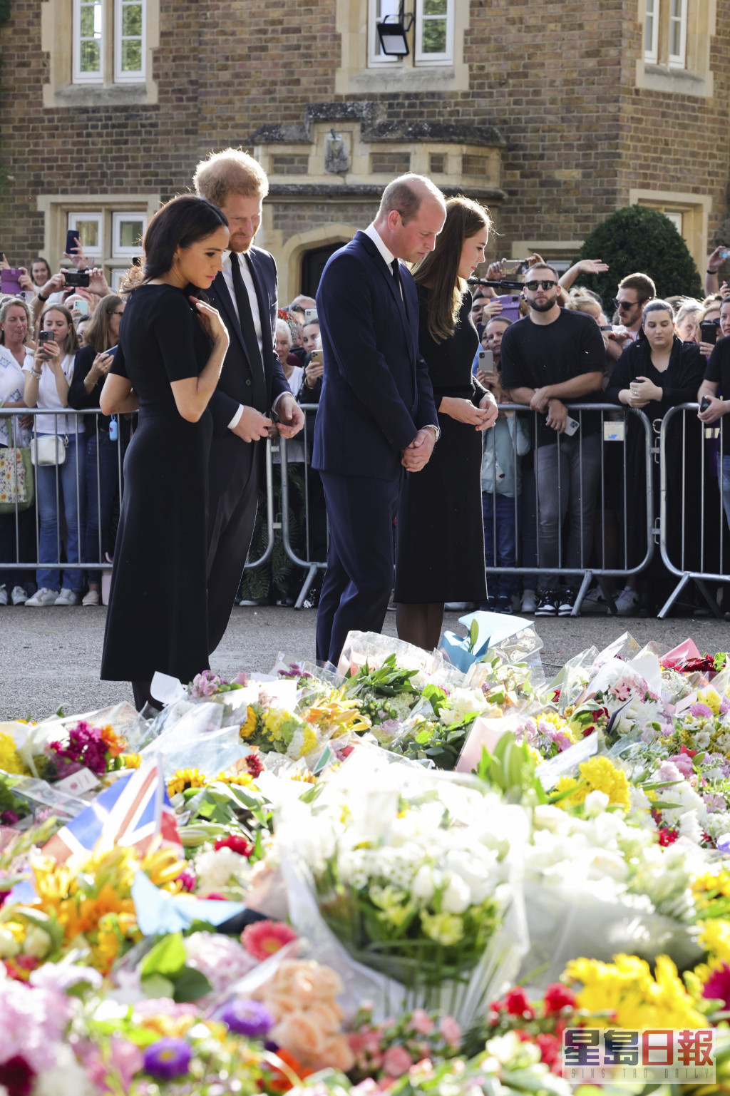 4人用心看民眾擺放在溫莎堡閘外悼念女皇的鮮花及留言。AP