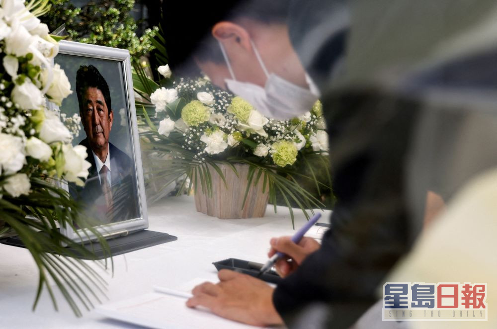 日本东京自民党总部的祭坛上，一位哀悼者在已故日本前首相安倍晋三的照片前签名。路透社图片