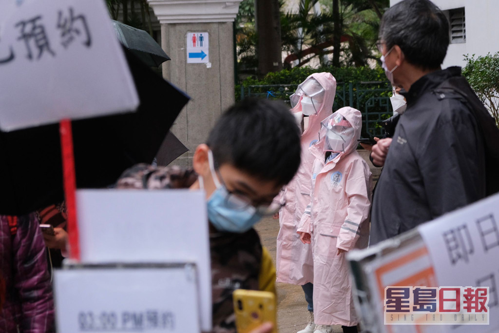 市民帶同小朋友在雨中排隊接種疫苗。