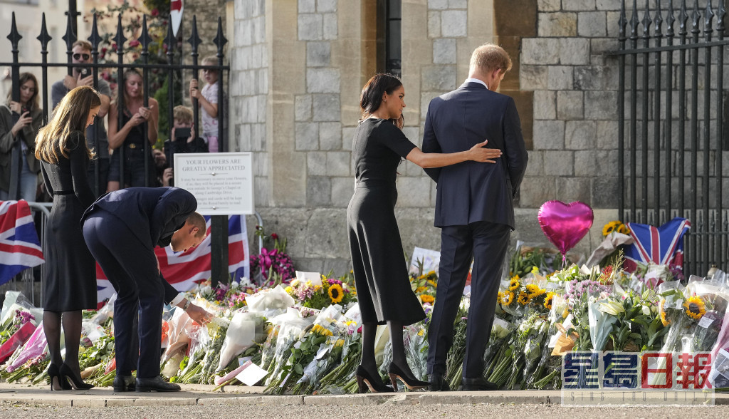 4人用心看民眾擺放在溫莎堡閘外悼念女皇的鮮花及留言。AP