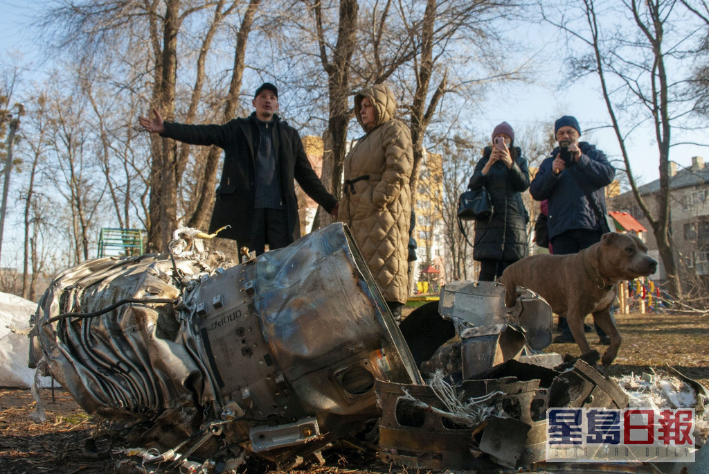 哈爾科夫市民重新外出，並站在空襲遺下的一堆武器碎片上。AP
