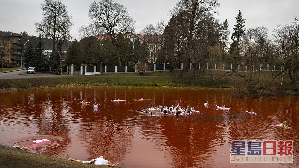 數十名示威者將俄駐立陶宛大使館前的池塘以生態染劑染成「血湖」。路透社圖片