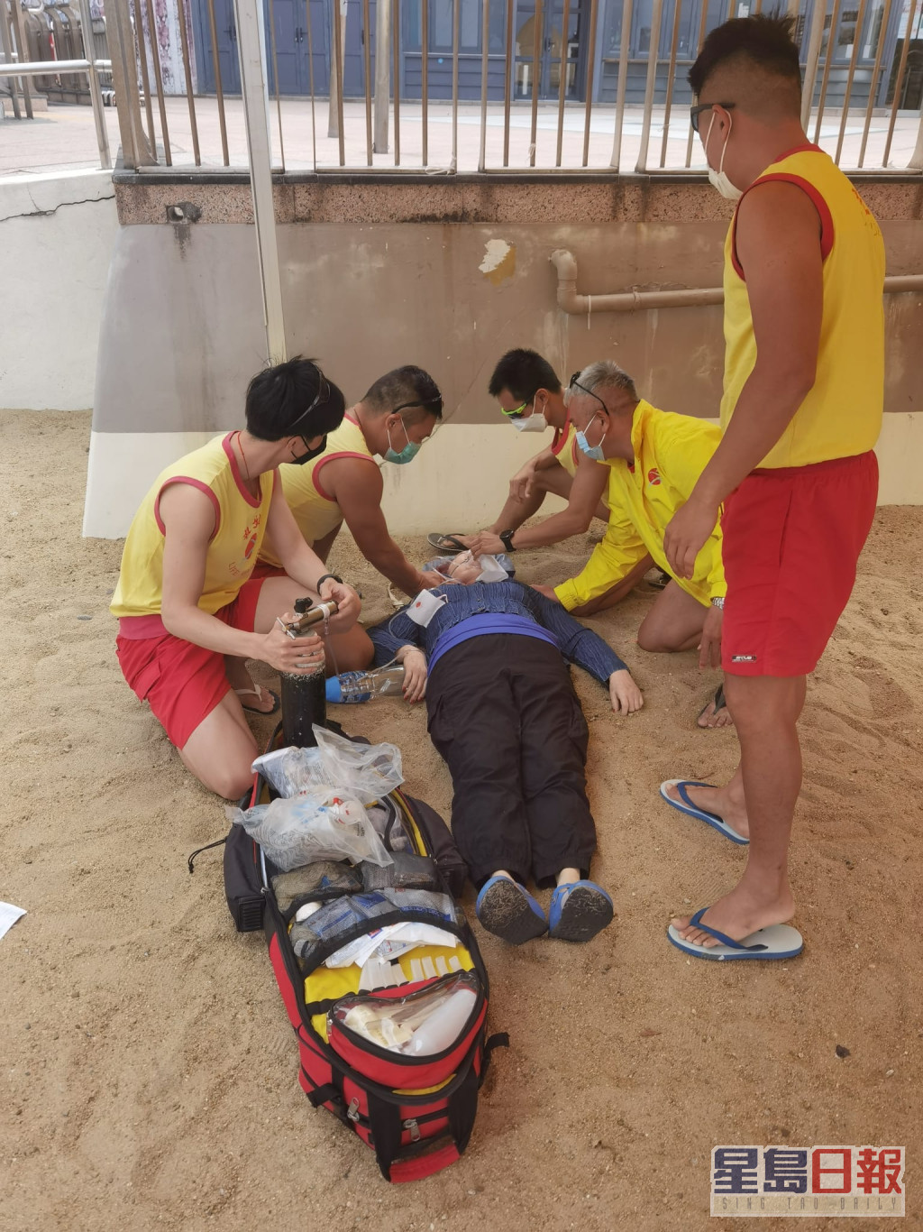 一名女子昏迷倒卧在沙滩上，救生员为事主急救。港九拯溺员工会FB图片