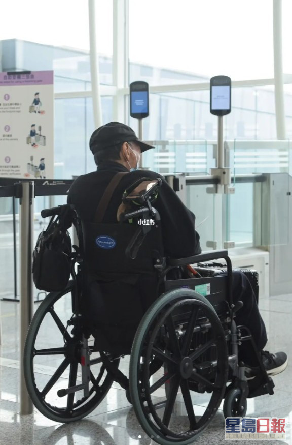 袁祥仁坐在轮椅上等候上机。